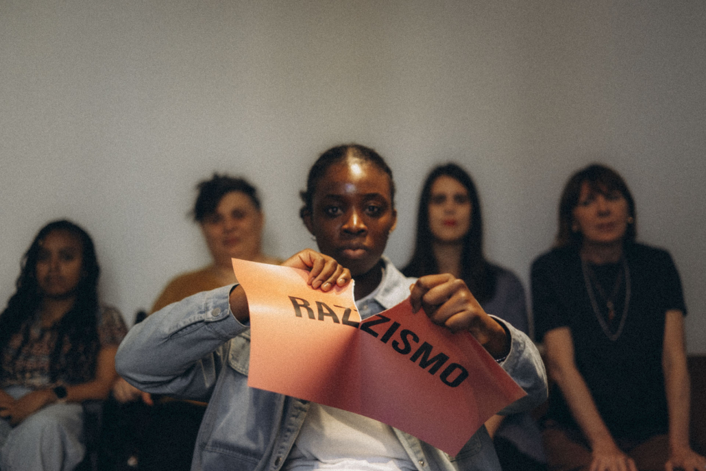 Ragazza strappa cartello con scritto Razzismo